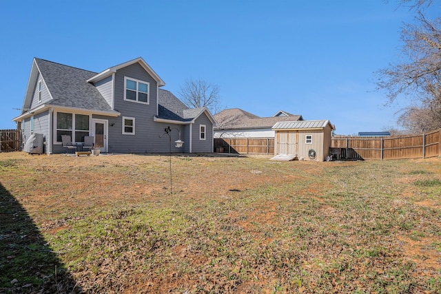 rear view of property with a fenced backyard, a shed, a lawn, and an outbuilding