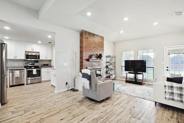 living room with a brick fireplace and light hardwood / wood-style flooring