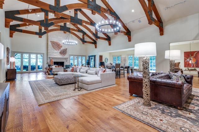 living room with high vaulted ceiling, a fireplace, wood-type flooring, rail lighting, and an inviting chandelier