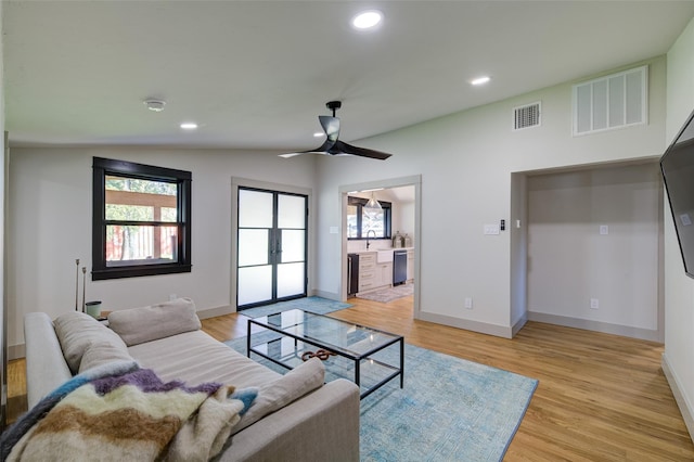 living room with lofted ceiling, sink, a wealth of natural light, and light hardwood / wood-style floors