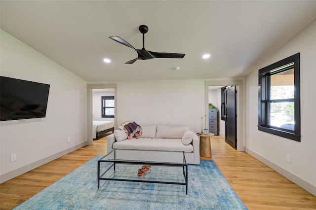 living room featuring ceiling fan, lofted ceiling, and light hardwood / wood-style flooring