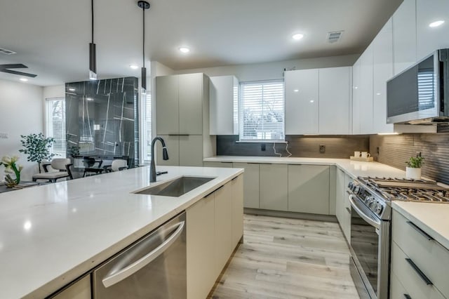 kitchen with a healthy amount of sunlight, appliances with stainless steel finishes, decorative light fixtures, and sink