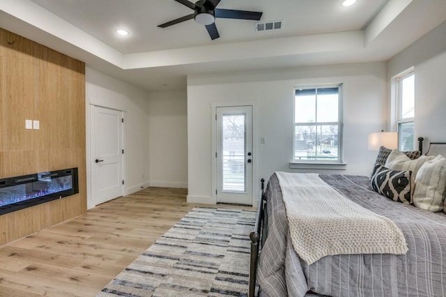 bedroom featuring access to outside, a raised ceiling, ceiling fan, and light wood-type flooring