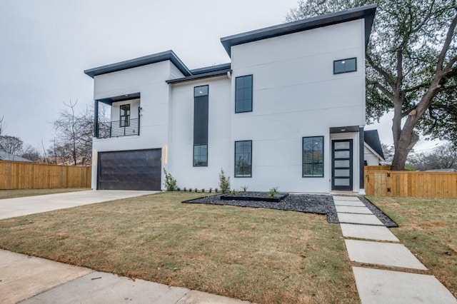 contemporary home with a garage, fence, driveway, stucco siding, and a front yard