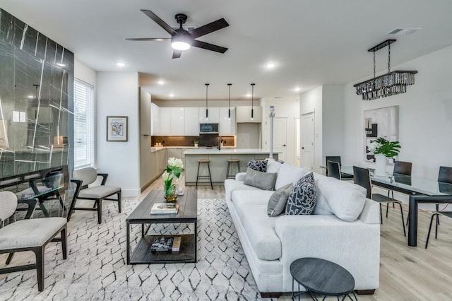 living room featuring a ceiling fan, light wood-type flooring, visible vents, and recessed lighting