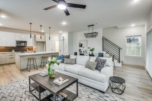 living room with sink, light hardwood / wood-style floors, and ceiling fan