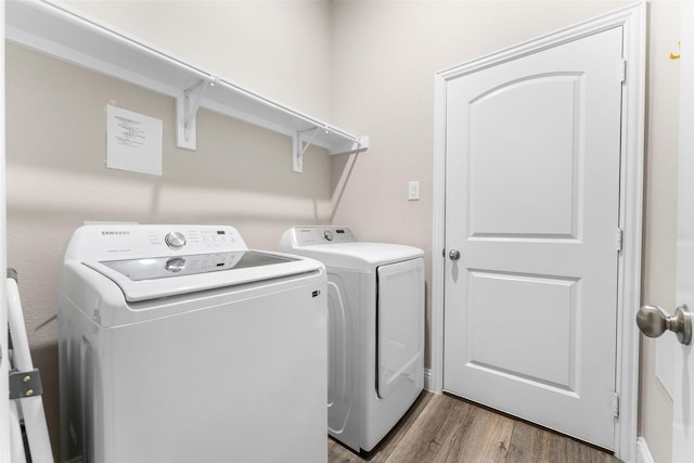 washroom with hardwood / wood-style floors and washing machine and dryer