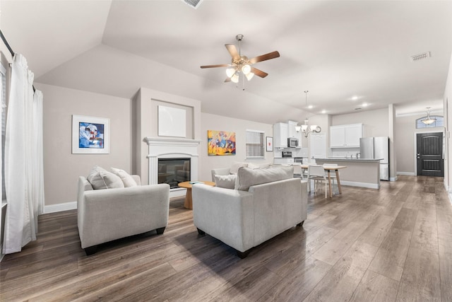 living room featuring dark hardwood / wood-style flooring, ceiling fan with notable chandelier, and lofted ceiling