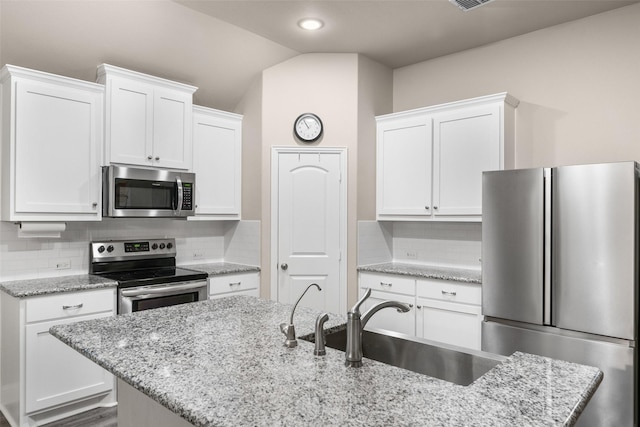 kitchen with white cabinetry, appliances with stainless steel finishes, sink, and an island with sink