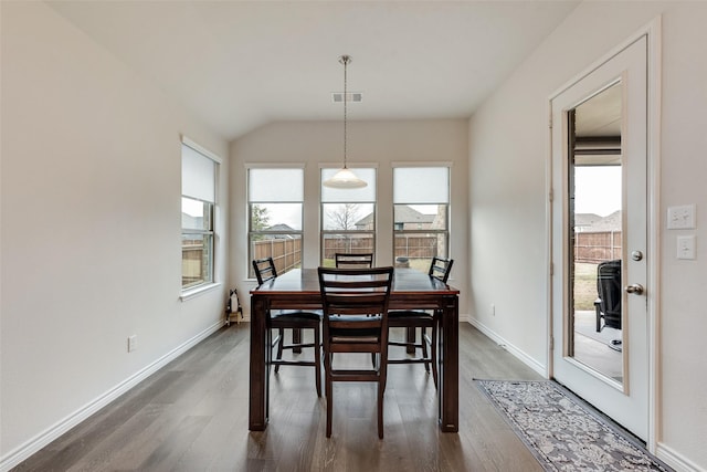 dining area featuring dark hardwood / wood-style flooring and vaulted ceiling