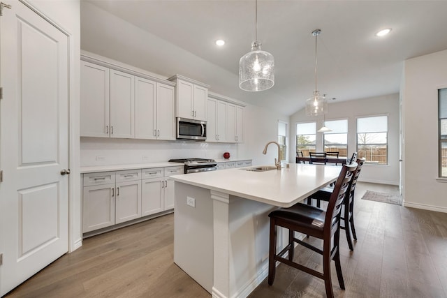 kitchen with sink, a breakfast bar area, a center island with sink, pendant lighting, and stainless steel appliances