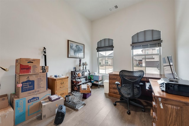 office area featuring a towering ceiling and light wood-type flooring