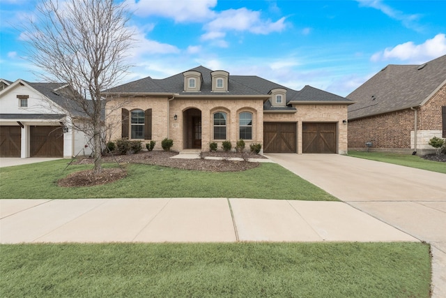 french country inspired facade featuring a garage and a front yard