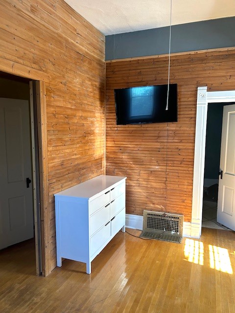 unfurnished living room with hardwood / wood-style flooring and wood walls