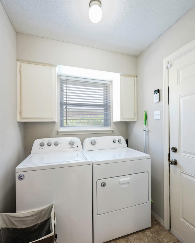 laundry area featuring cabinets, a textured ceiling, and washer and clothes dryer