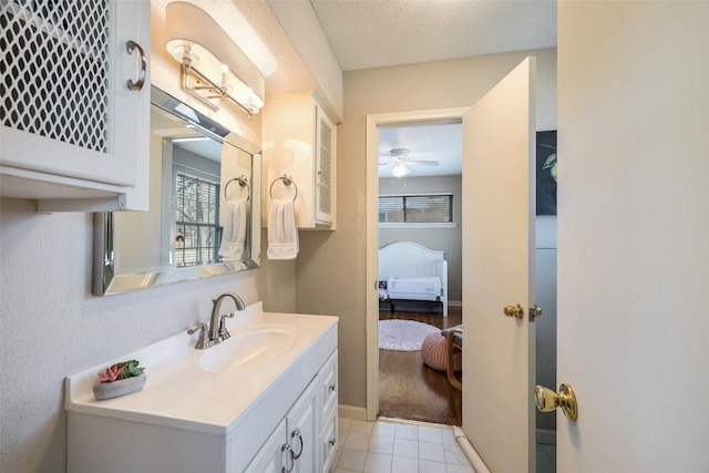 bathroom with tile patterned floors, ceiling fan, vanity, and a textured ceiling