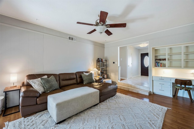 living area with ceiling fan, visible vents, wood finished floors, and built in study area