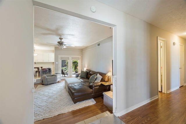 living room featuring ceiling fan, hardwood / wood-style floors, a textured ceiling, and french doors