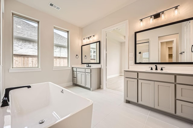 4405 Tower Bluff Rd, Midlothian, TX 76065 - full bath featuring two vanities, a freestanding bath, tile patterned floors, and baseboards