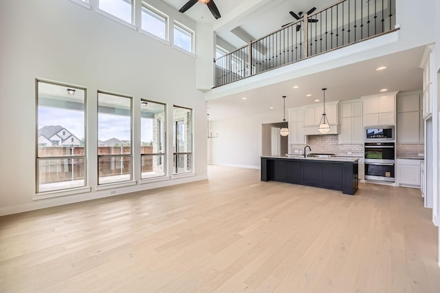 4405 Tower Bluff Rd, Midlothian, TX 76065 - living area featuring a ceiling fan, a towering ceiling, light wood-style floors, and baseboards