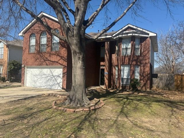 view of front of home featuring driveway, an attached garage, fence, a front lawn, and brick siding