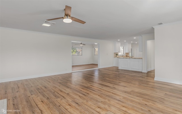 unfurnished living room featuring ornamental molding, light wood-type flooring, and baseboards