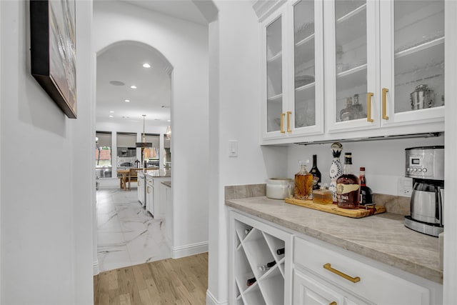 bar with white cabinetry and light stone countertops