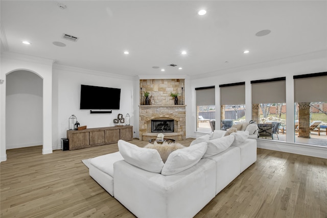 living room featuring a fireplace, crown molding, and light hardwood / wood-style flooring