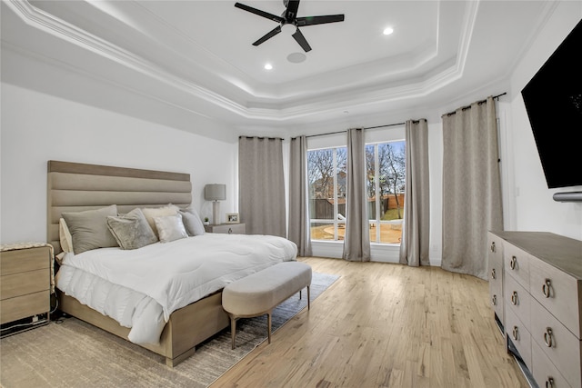 bedroom with ceiling fan, ornamental molding, a raised ceiling, and light hardwood / wood-style floors