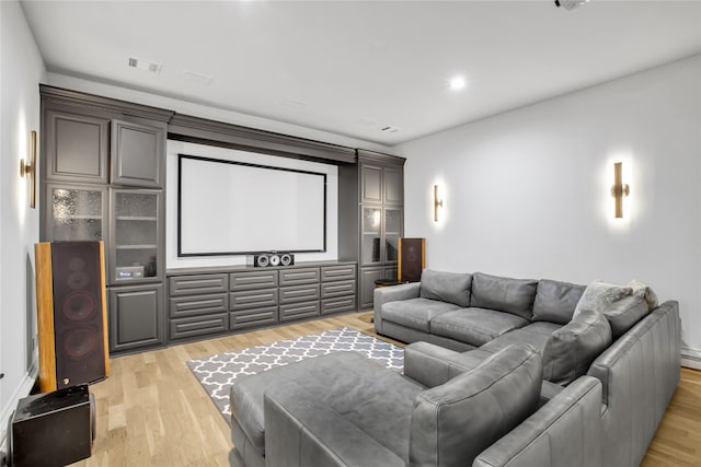 cinema with light hardwood / wood-style flooring and a baseboard heating unit