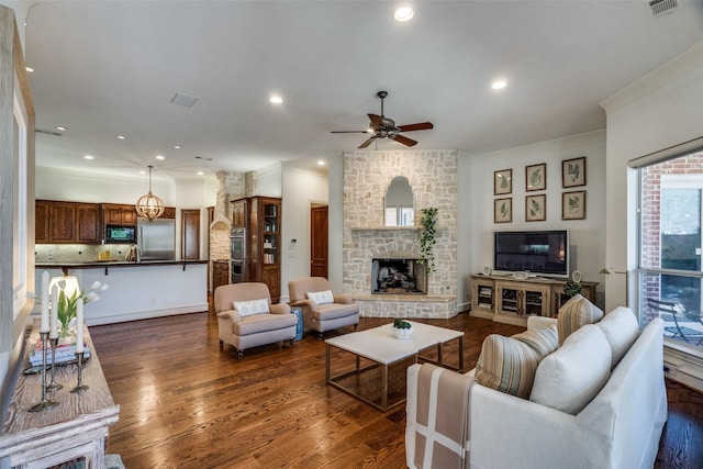 living room featuring ornamental molding, dark wood-type flooring, ceiling fan, and a fireplace