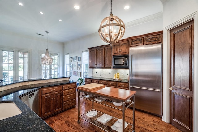 kitchen featuring built in appliances, hanging light fixtures, and an inviting chandelier