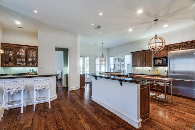 kitchen featuring black microwave, pendant lighting, a breakfast bar, and high end refrigerator