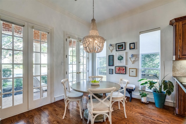 dining area featuring dark wood-type flooring, ornamental molding, french doors, and a chandelier