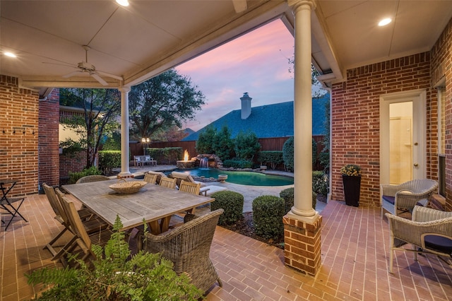 patio terrace at dusk featuring pool water feature, ceiling fan, and a fenced in pool