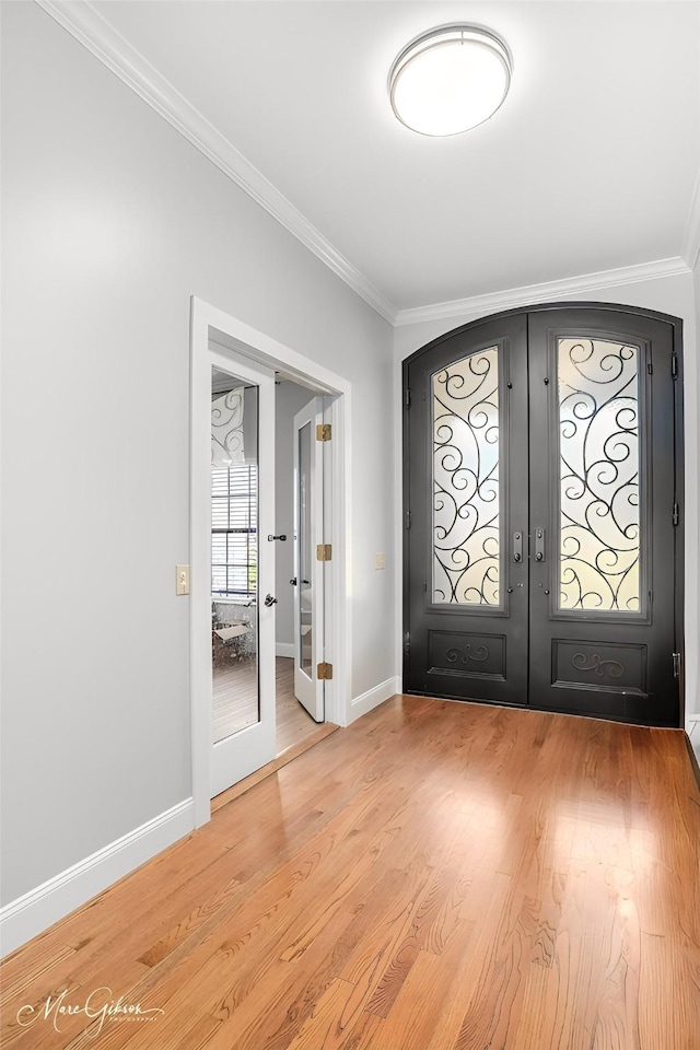 foyer with french doors, ornamental molding, and wood-type flooring