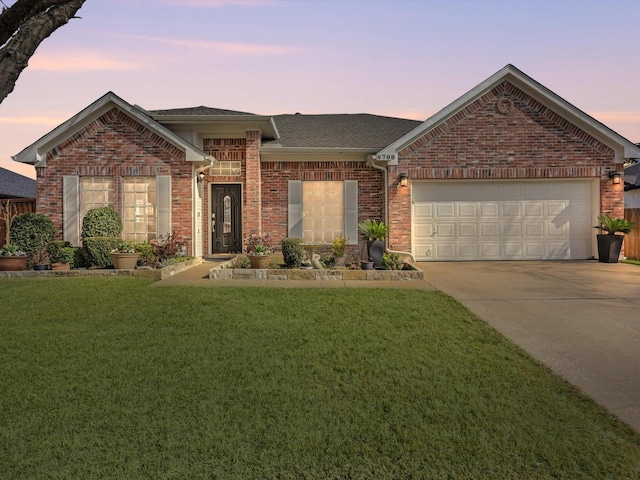 ranch-style home with driveway, an attached garage, a front lawn, and brick siding