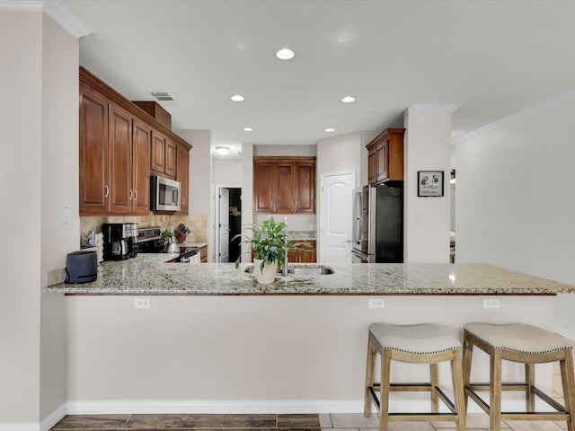 kitchen with recessed lighting, a peninsula, visible vents, appliances with stainless steel finishes, and light stone countertops