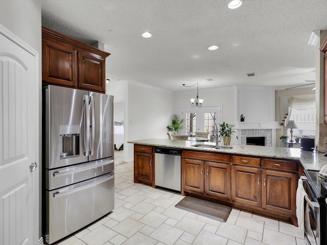 kitchen with a textured ceiling, light stone counters, recessed lighting, a sink, and appliances with stainless steel finishes