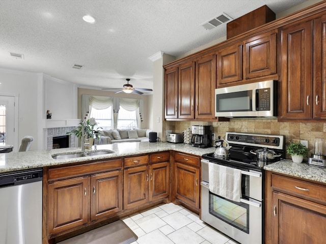 kitchen with visible vents, decorative backsplash, appliances with stainless steel finishes, open floor plan, and a sink