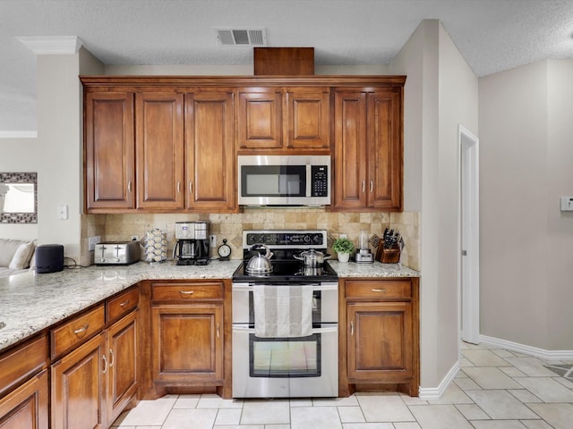 kitchen with appliances with stainless steel finishes, brown cabinets, and tasteful backsplash