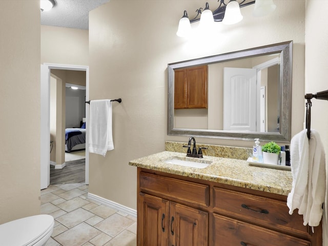 ensuite bathroom featuring toilet, vanity, ensuite bath, a textured ceiling, and tile patterned floors