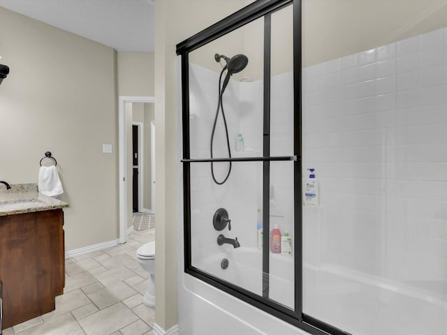 bathroom with enclosed tub / shower combo, toilet, vanity, and baseboards