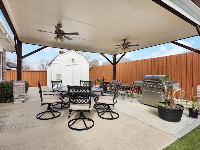 view of patio with ceiling fan, outdoor dining area, a fenced backyard, an outdoor structure, and a storage unit