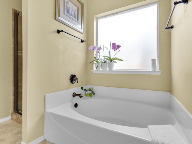 bathroom with a stall shower, a garden tub, baseboards, and tile patterned floors