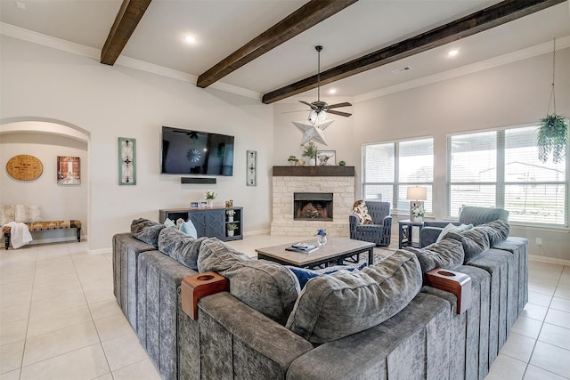 tiled living room featuring beamed ceiling, ceiling fan, and a stone fireplace