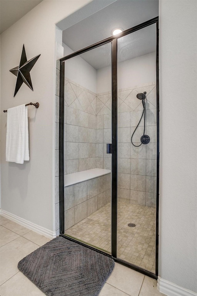 bathroom with a shower with door and tile patterned floors