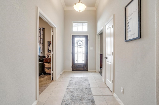 foyer entrance with crown molding and light tile patterned floors