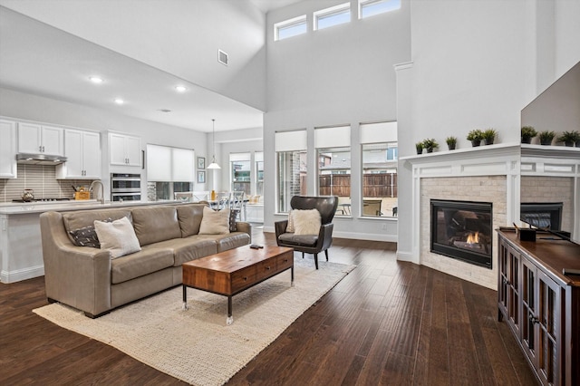 living room featuring a healthy amount of sunlight, dark hardwood / wood-style flooring, and a brick fireplace