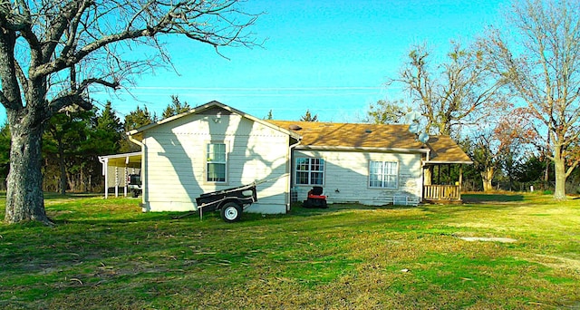 rear view of property with an attached carport and a yard